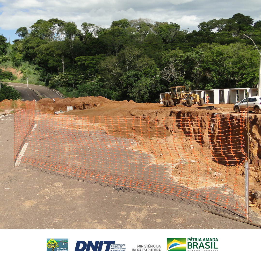 Tela protetora de cor laranja cercando uma vala no meio de uma via de pista dupla pavimentada
