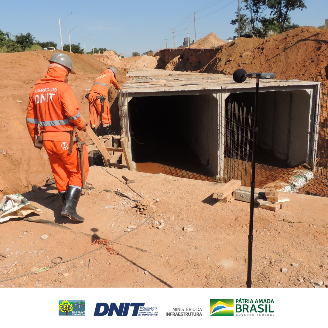 Sonômetro posicionado próximo a homens trabalhando, em galeria de concreto do sistema de drenagem